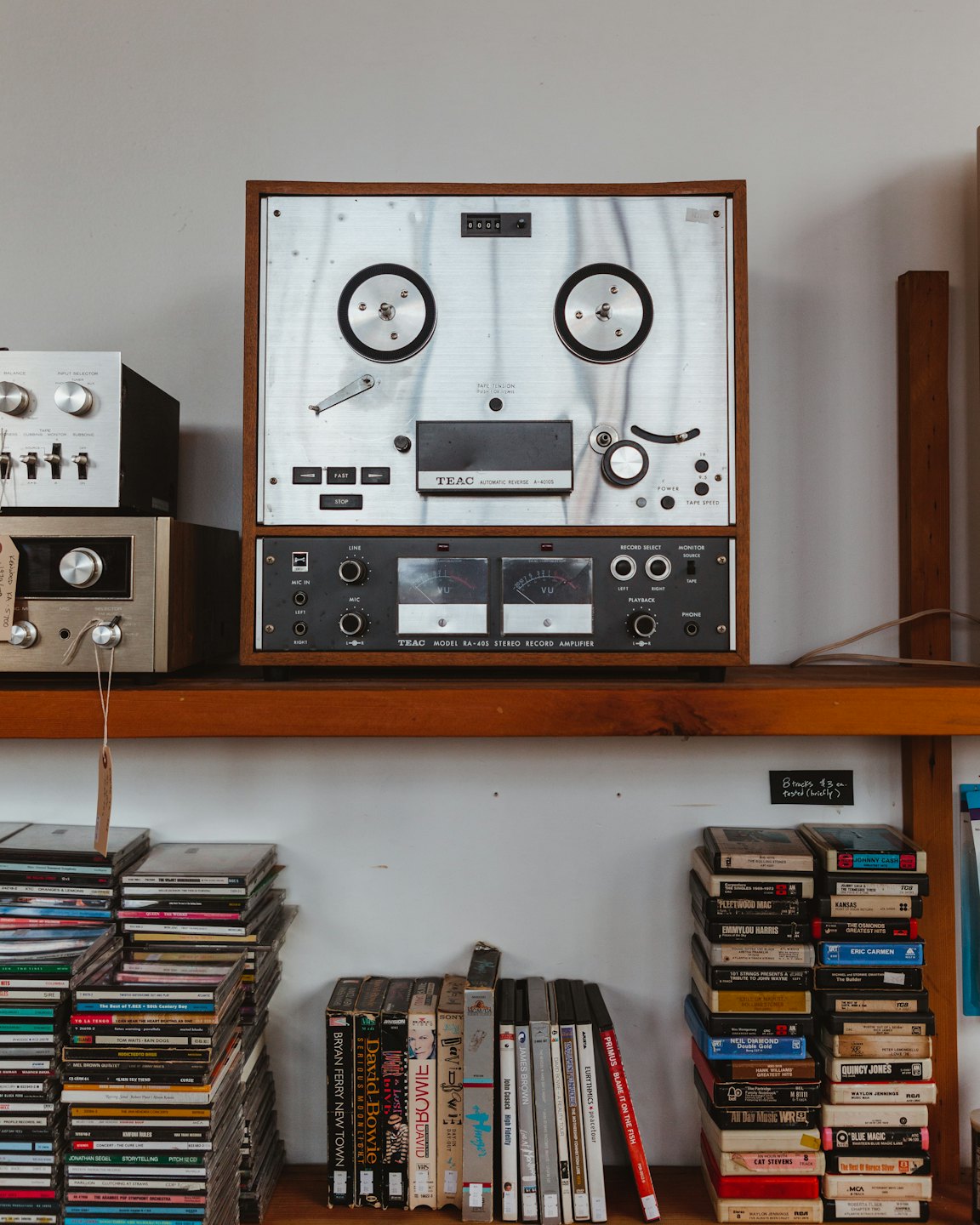 Vintage reel-to-reel player and amplifier on a shelf.