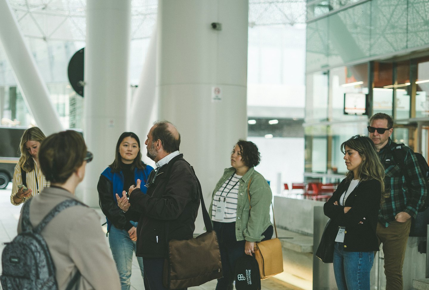 A group of attendees listens to a speaker in a modern building.