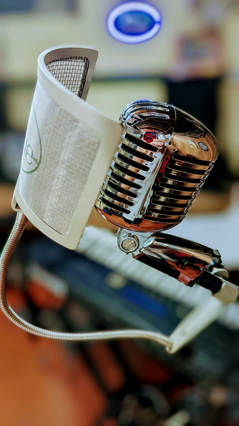 A vintage chrome microphone sits on a recording studio stand.